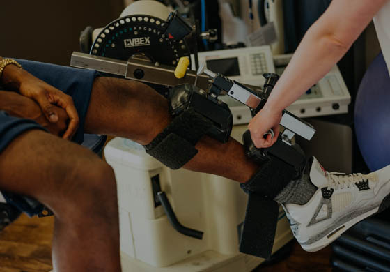 Young male's leg in a Cybex machine with a therapist's arm completing the testing in the Sport Medicine Clinic