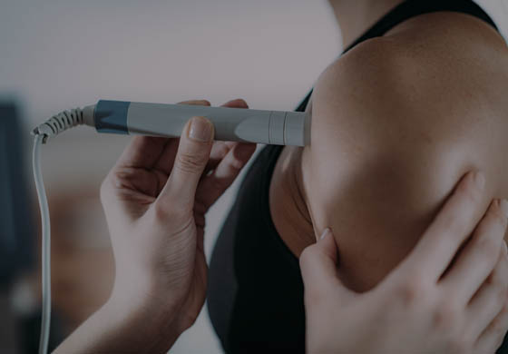 Female practitioner's hand using the laser on a young, female patient's shoulder